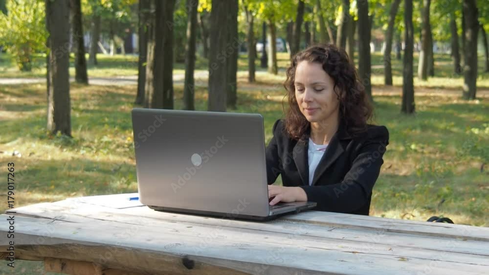 A girl in a business suit is working with a laptop in nature. A girl in a business suit is working with a laptop in nature.