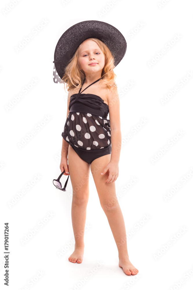 Attractive cute little girl in in black swimwear and black hat hold glasses Attractive cute little girl in in black swimwear and black hat hold glasses