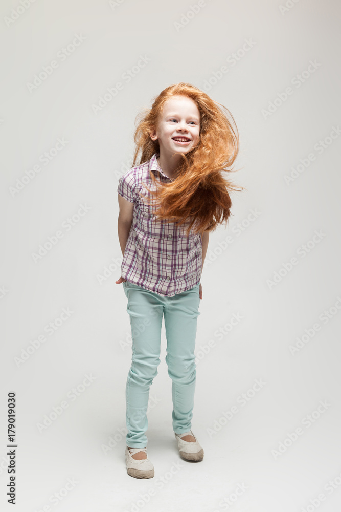 Adorable cute redhead little girl in plaid shirt, bright blue trousers and white boots Adorable cute redhead little girl in plaid shirt, bright blue trousers and white boots