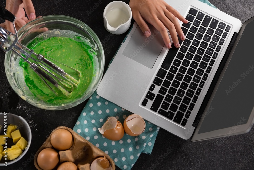 Fotografie Woman using a laptop after preparing batter