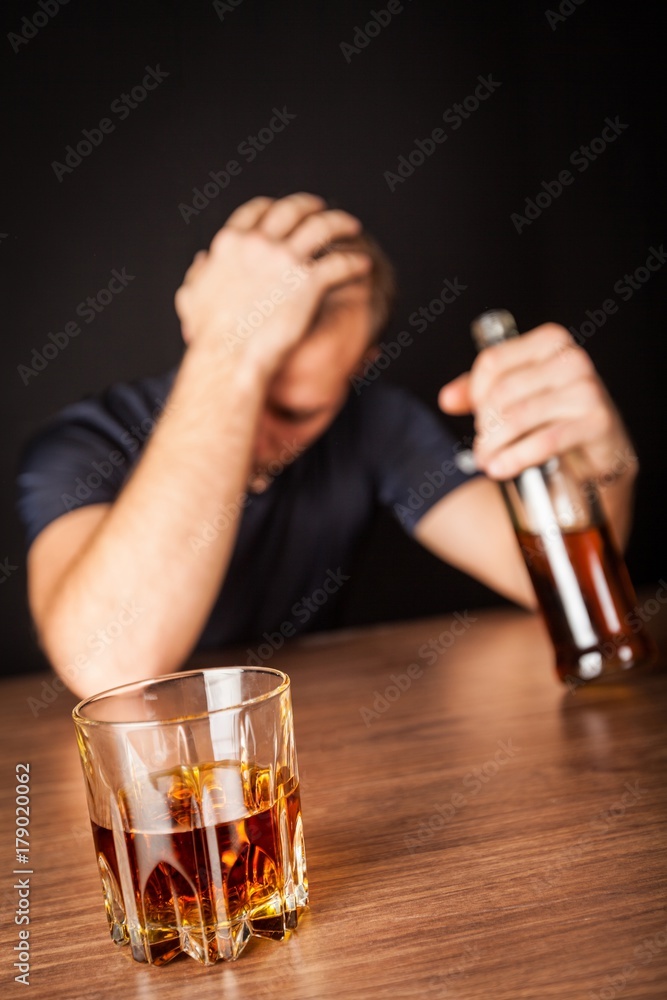 Drunk / Sad Man with Bottle and Glass of Liquor At Bar Counter
