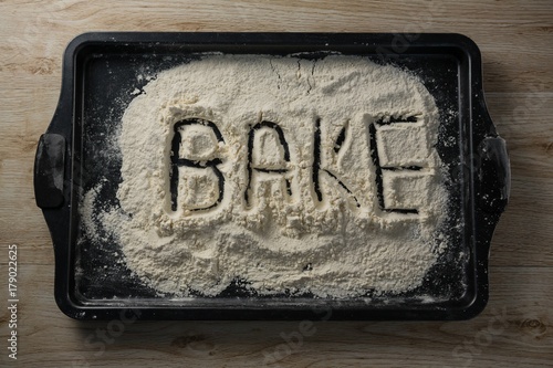 The word bake written on flour on a baking tray