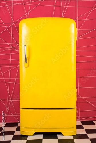old vintage yellow refrigerator on a pink background