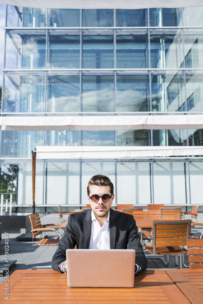 Male businessman or worker in black suit at the table and working on computer. Male businessman or worker in black suit at the table and working on computer.