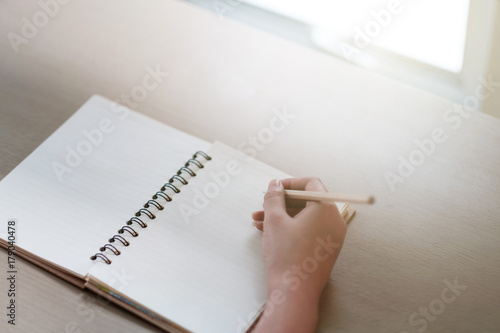 hand woman writing a note book on the table and frame with sunshine