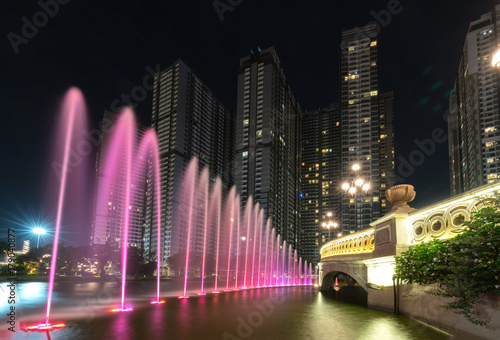 Ho Chi Minh City, Vietnam - November 30th, 2017: A state of the art fountain at night with colorful lights shimmering, behind the skyscrapers in the urban park development in Ho Chi Minh City. Minh, V