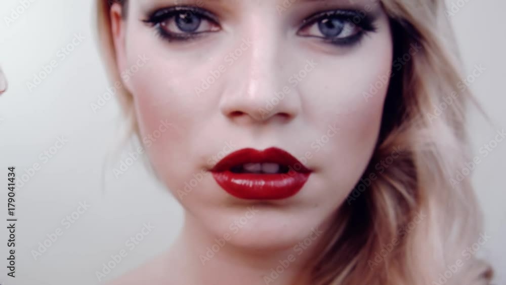 Beautiful girl holds lipstick in front her,opens her lipstick,looks into camera, smiles.Shows red lipstick.In studio on white background.Beauty salon.Hairstyle retro style,hollywood wave,bright makeup Beautiful girl holds lipstick in front her,opens her lipstick,looks into camera, smiles.Shows red lipstick.In studio on white background.Beauty salon.Hairstyle retro style,hollywood wave,bright makeup