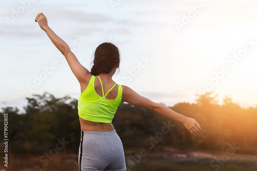 Young asian woman runner raise her hand up to resting after workout session