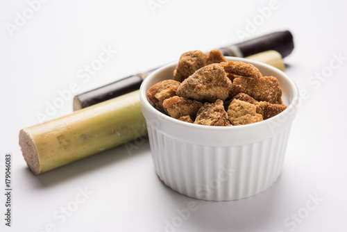 Jaggery and sugar cane - by-products of sugar cane called gur / gud or jaggery. Jaggery is a traditional non-centrifugal cane sugar consumed in Asia, Africa. Selective focus
 photo