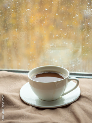 Cup of coffee with homemade biscuits on the blanket  raindrops on the window