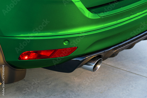 Rear bumper of a green car with exhaust pipe, modern car exterior details