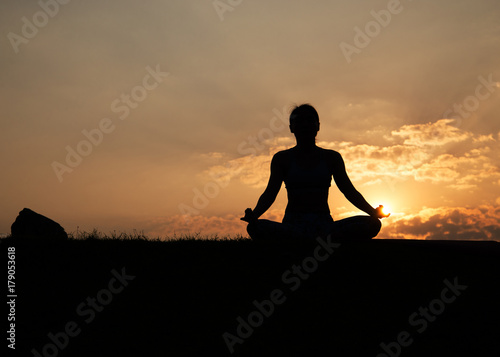 Woman sitting meditation outdoors,silhouette.