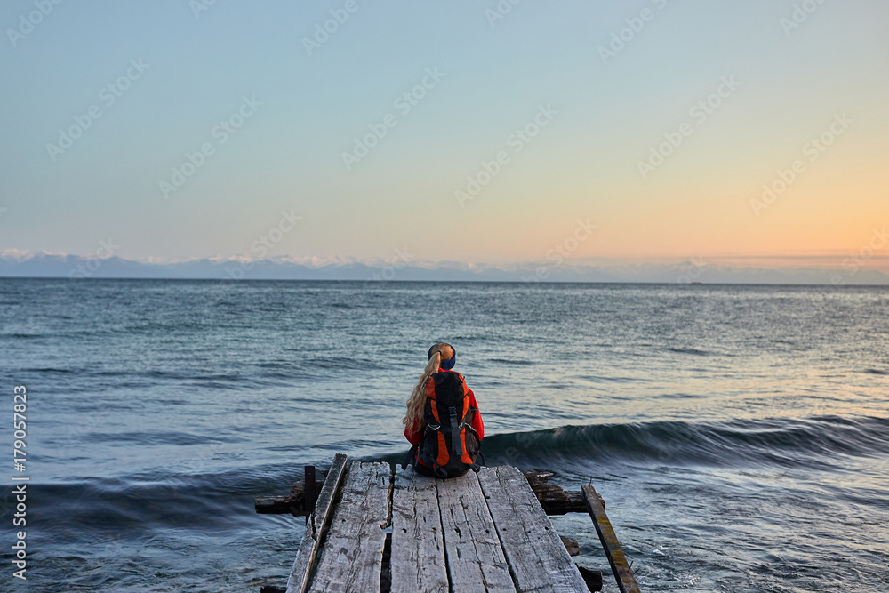 Traveler wearing in warm clothing with backpack enjoying view of sea
