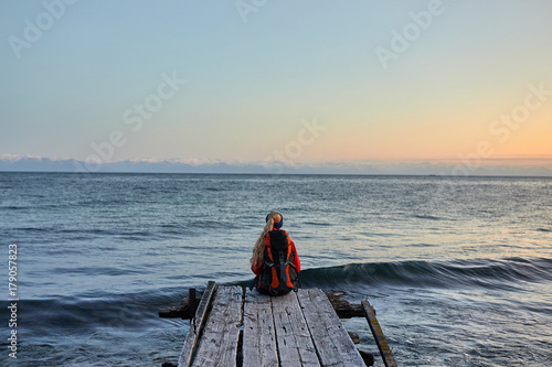 Traveler wearing in warm clothing with backpack enjoying view of sea © xfasss88
