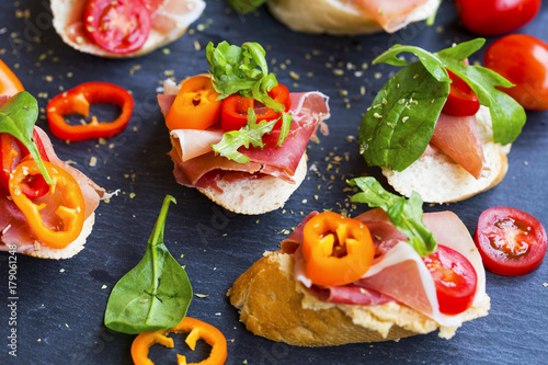 Cuadro en lienzo Canapes appetizer with prosciutto ham, pepper slices, tomatoes and green spinach