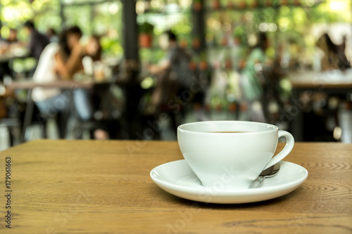 Cup of coffee on wooden table with blur background