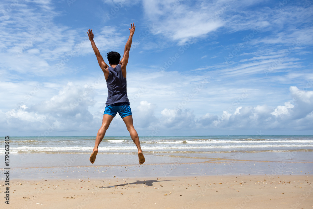 Happy man jumping at the beach in blue sky