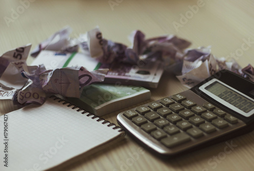 wrinkled banknotes, Notepad, calculator are on the table