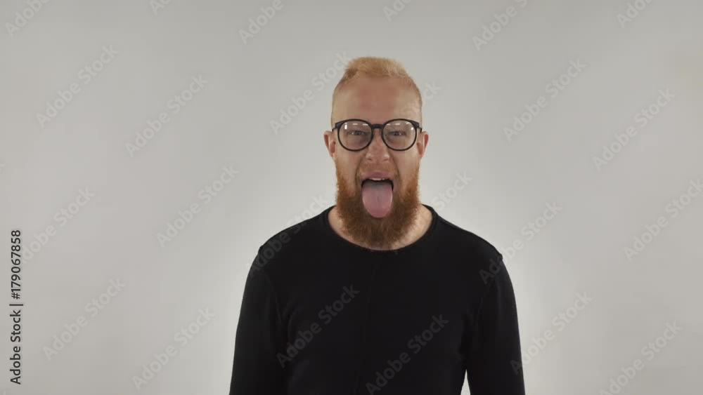 Portrait man showing tongue. Handsome funny guy have fun in studio. Redhead millennial person with beard wearing in casual pullover fool around. Portrait man showing tongue. Handsome funny guy have fun in studio. Redhead millennial person with beard wearing in casual pullover fool around.