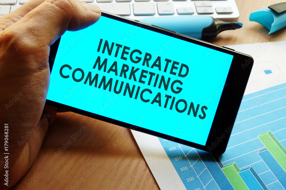 Naklejka premium Hand holding smartphone with words integrated marketing communications.