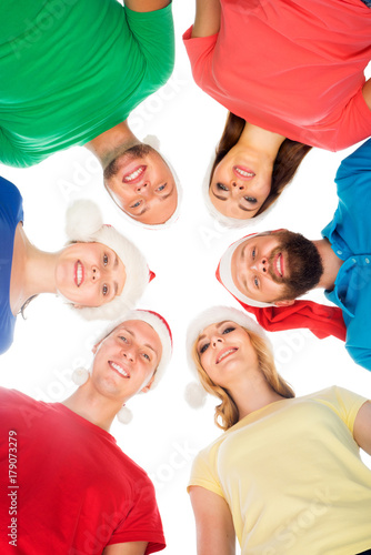 Different boys and girls in Christmas hats embracing together isolated on white. Friendship and New Year, X-mas, Xmas celebration concept.