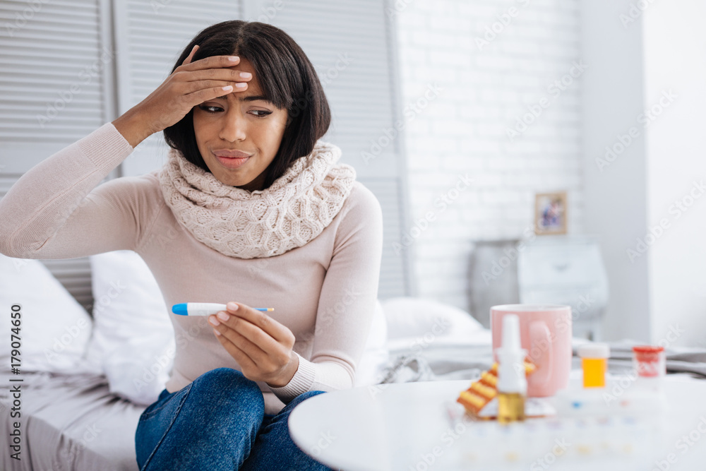 Upset woman with high temperature looking at the medicines Upset woman with high temperature looking at the medicines