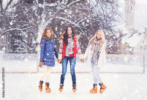 Beautiful skating girls. Open air rink at winter. Falling snow. Christmas concept.