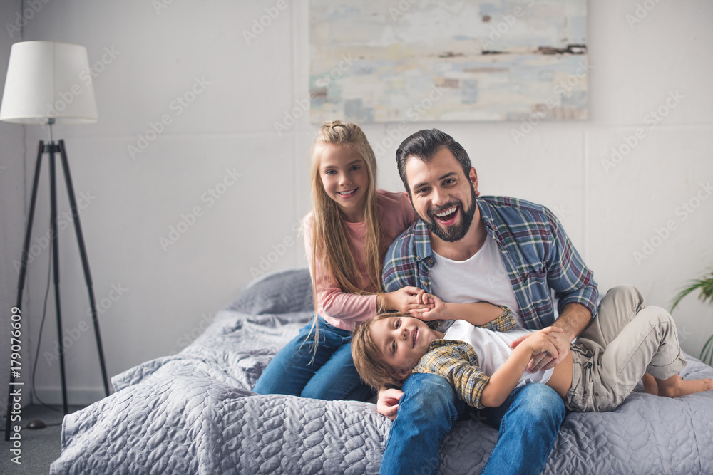 father and kids resting on bed - obrazy, fototapety, plakaty 
