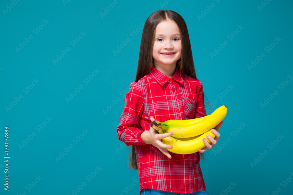 Pretty, little girl in checkered shirt with brunet hair hold fruit