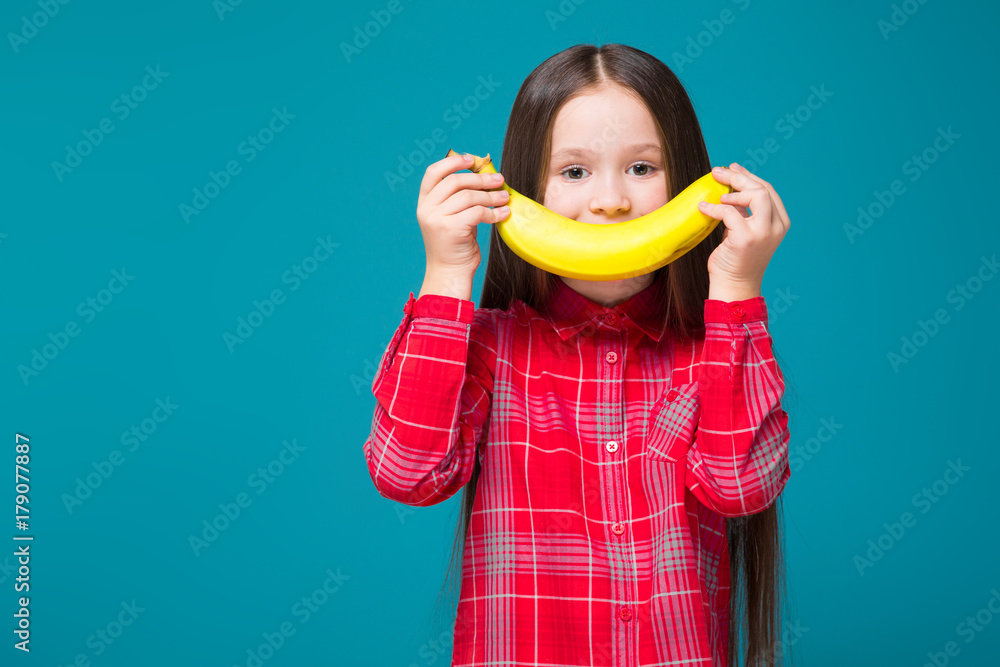 Pretty, little girl in checkered shirt with brunet hair hold fruit Pretty, little girl in checkered shirt with brunet hair hold fruit