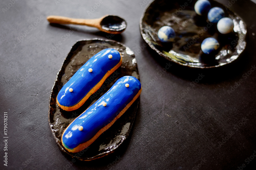 Blue eclairs and candy in blue colors. On a dark background. Pastry arts Blue eclairs and candy in blue colors. On a dark background. Pastry arts