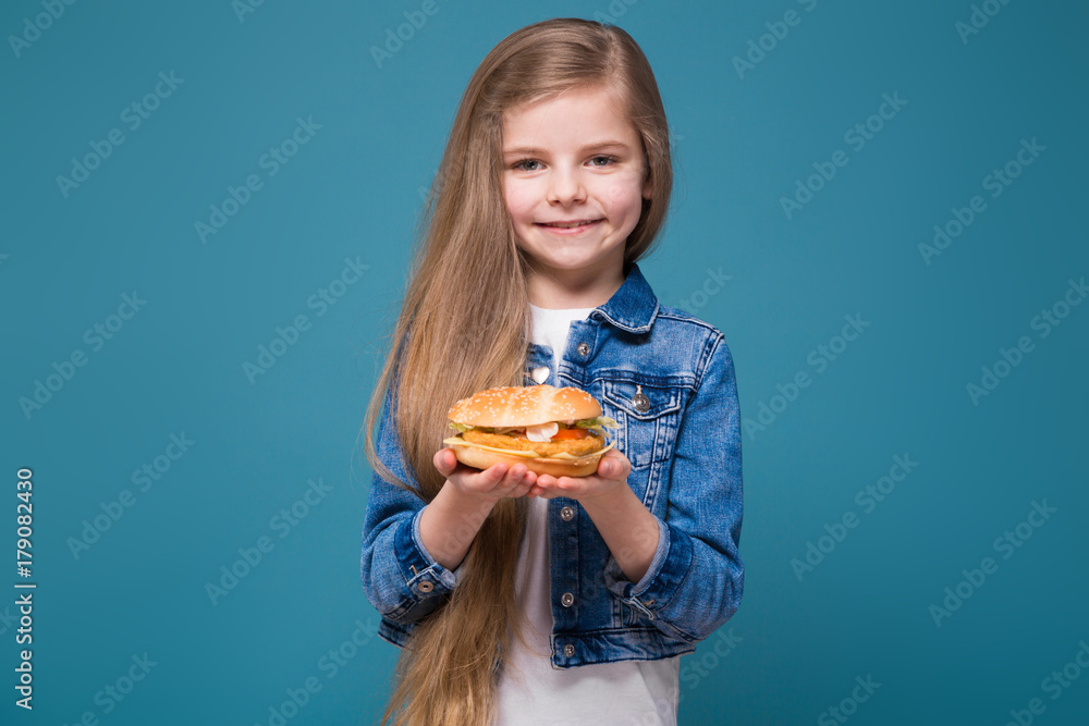 Little pretty girl in jean jacket with long brown hair hold a burger Little pretty girl in jean jacket with long brown hair hold a burger