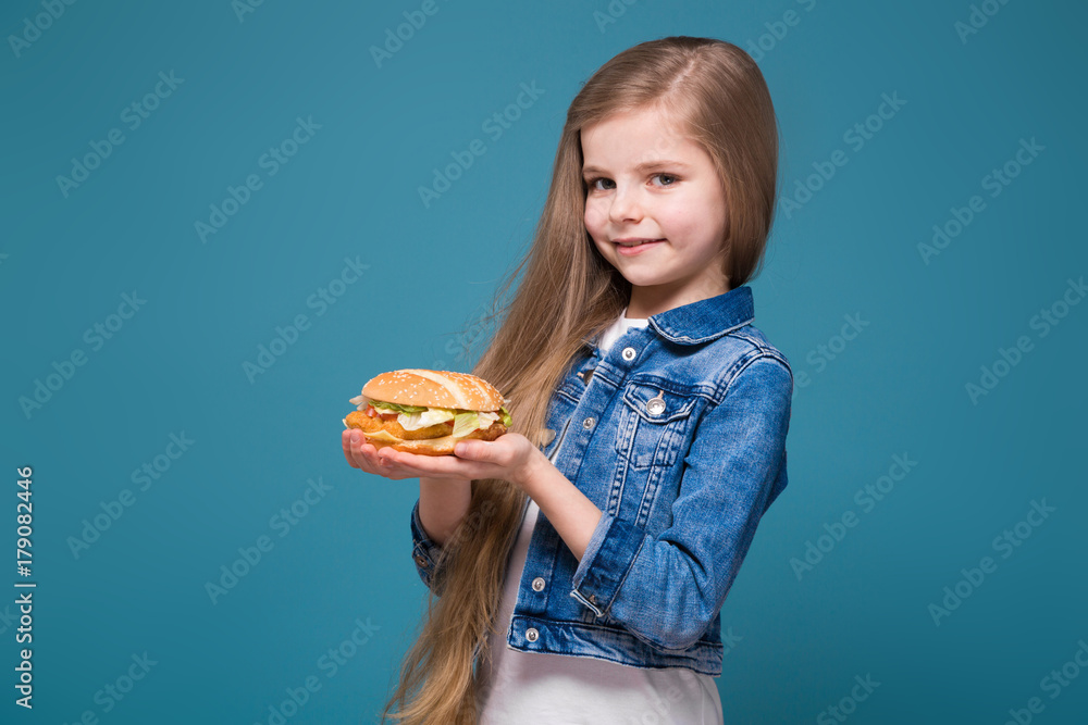 Little pretty girl in jean jacket with long brown hair hold a burger Little pretty girl in jean jacket with long brown hair hold a burger