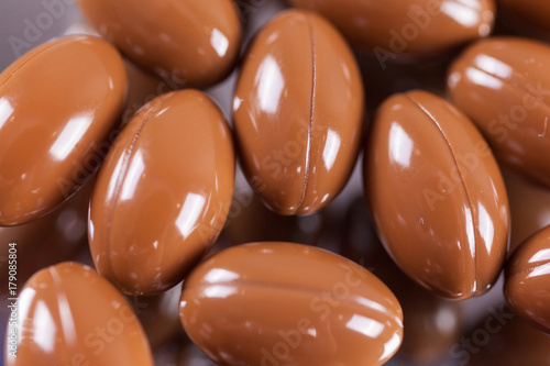 a scattering of brown capsules, tablets on a mirrored background