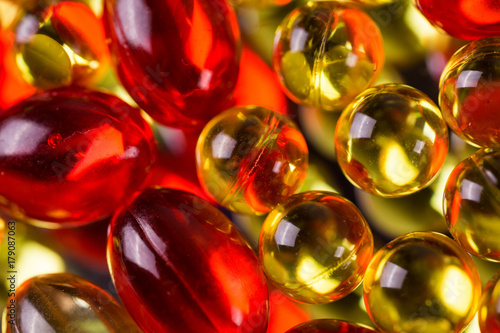 yellow and red medical capsules on a mirror surface