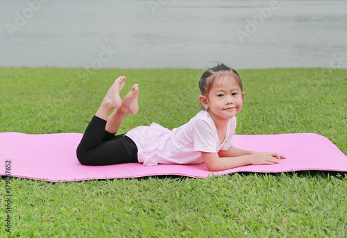 Close-up little asian child girl doing yoga in the public park.