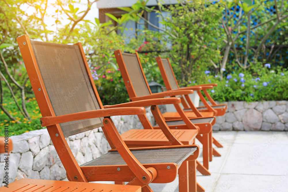 Wooden chairs set beside a pool.