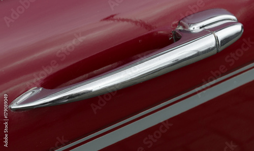 A retro chrome handle on a red car door