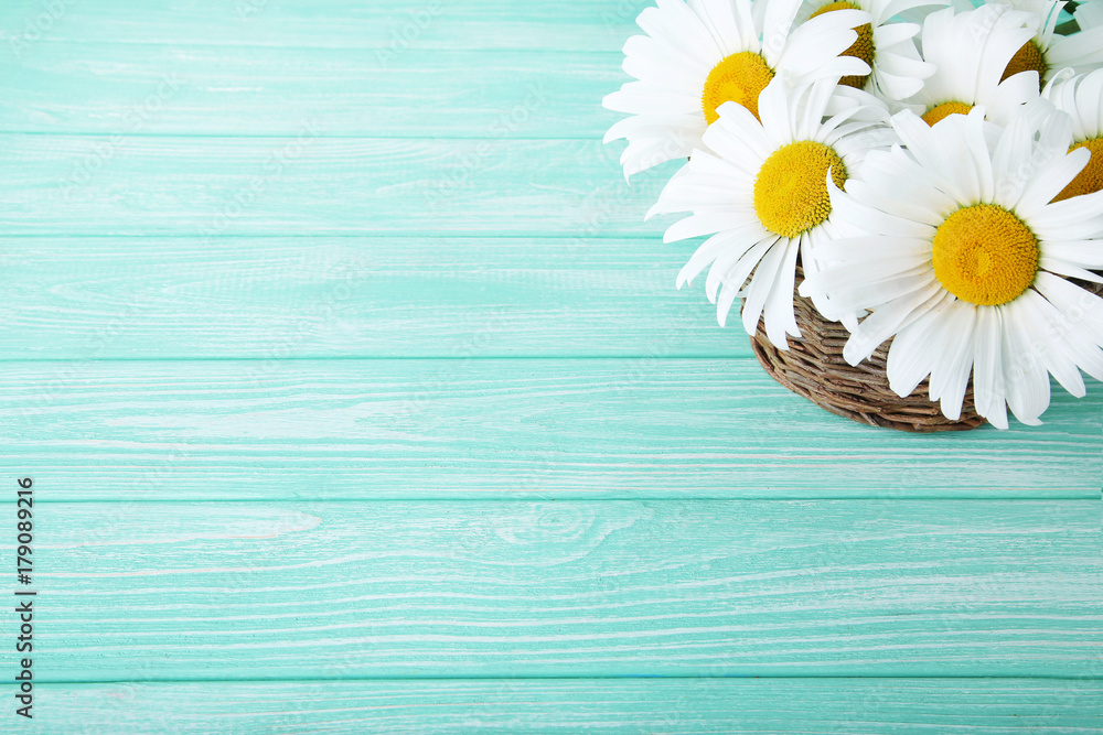 Obraz premium Bouquet of chamomile flowers in basket on mint wooden table