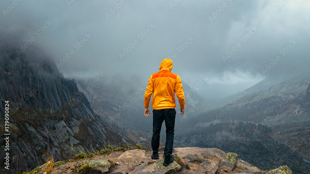 a man stands on the precipice of the mountain in the fog