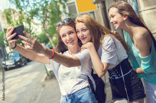Teenage girls taking selfie photo on the city street.