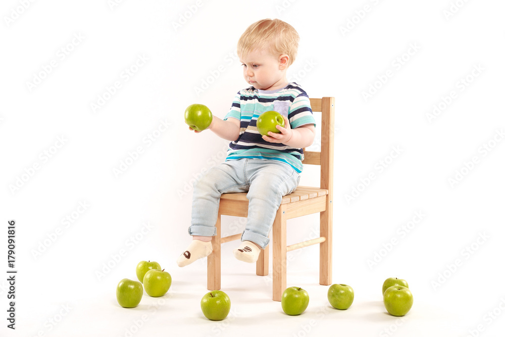 little boy sitting on a chair surrounded by apples little boy sitting on a chair surrounded by apples