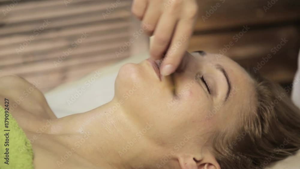 Acupressure on a female face. Chinese alternative massage with scraper gouache Acupressure on a female face. Chinese alternative massage with scraper gouache