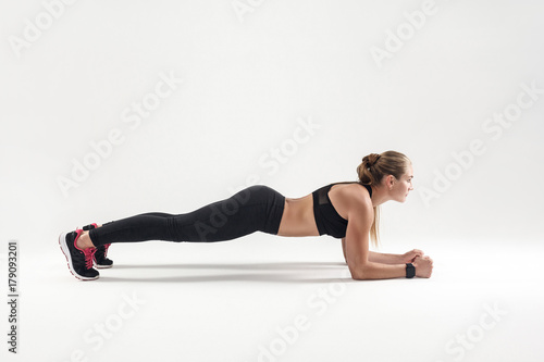 Balance and concentration. Strong blonde woman standing in plank photo