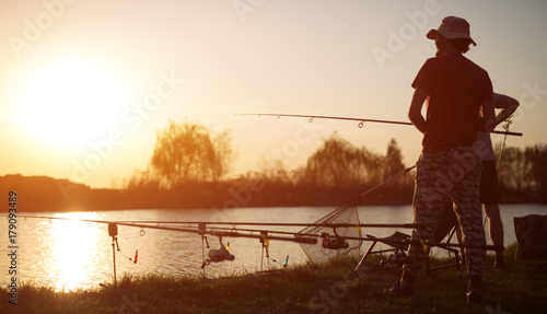 Young man fishing on lake at sunset enjoying hobby