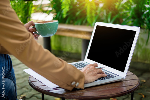 business woman hand working using laptop on table in garden.