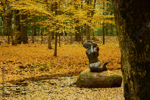 A sculpture of a mermaid in the pond. Autumn landscape. Golden autumn