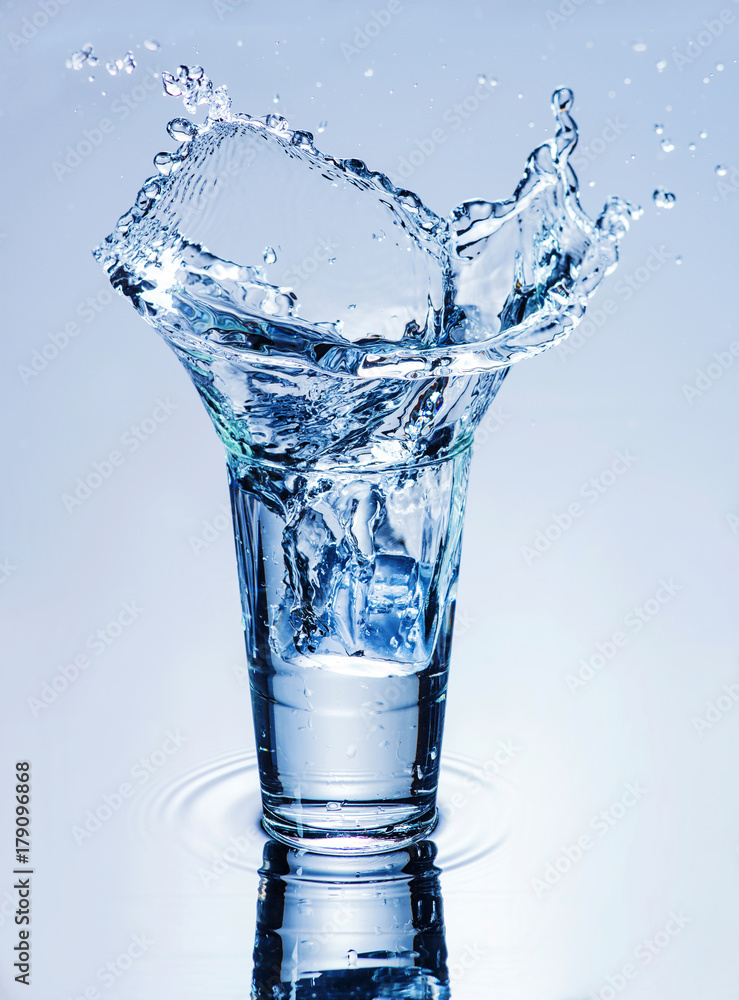 icecube splashing into a glass of water icecube splashing into a glass of water