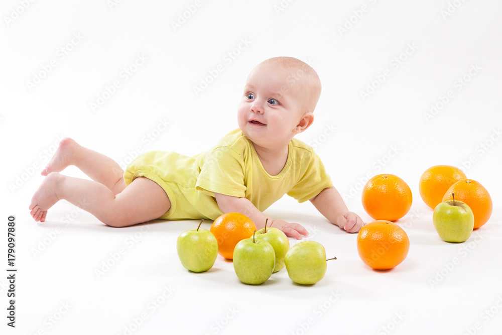 cute surprised baby looks at green apple on a white background cute surprised baby looks at green apple on a white background