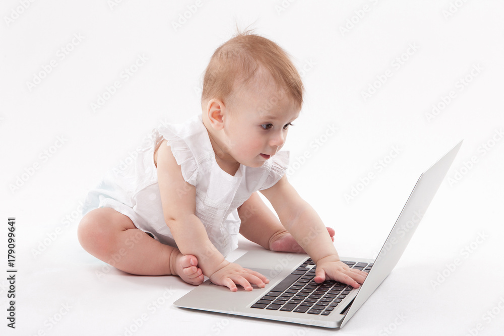 curious smiling child sitting near the laptop on a white background curious smiling child sitting near the laptop on a white background
